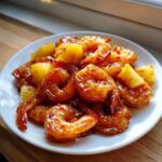 Close-up of glossy Sweet Chili Pineapple Shrimp served on a white plate, glistening with sauce.