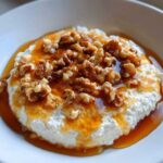 Close-up of sweet whipped ricotta dip topped with honey drizzle and chopped walnuts.