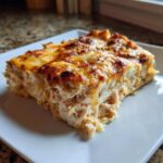 A close-up, appetizing slice of Texas King Ranch Chicken Casserole with a golden, bubbly cheese top.