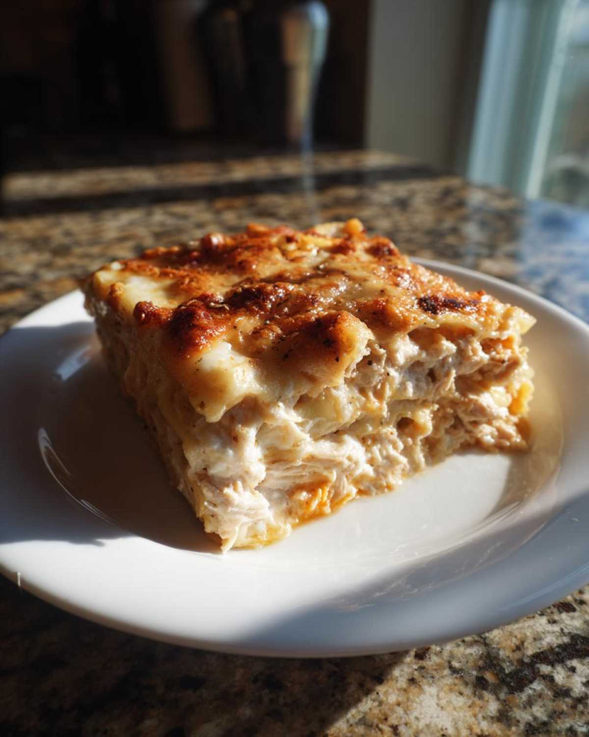 A close-up slice of creamy Texas King Ranch Chicken Casserole with a browned, cheesy top, served on a white plate.