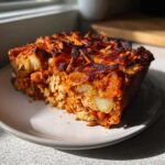 A close-up slice of Whole30 BBQ Chicken Casserole showing shredded chicken, potatoes, and a crispy, dark orange topping.