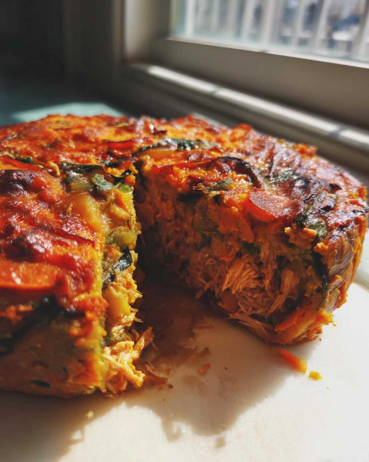 Close-up of a Whole30 BBQ Chicken Casserole with a slice removed, showing shredded chicken filling and vegetable layers.