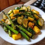 A close-up of vibrant, sautéed Asparagus with Zucchini and Squash, seasoned and served on a white plate.