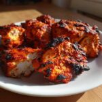 Close-up of juicy, bright red Baked Tandoori Chicken Oven pieces served on a white plate.