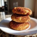 Three soft chewy Banana Snickerdoodle Cookies stacked on a white plate, coated in cinnamon sugar.