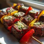 Close-up of grilled BBQ skewers featuring steak cubes topped with melting Cowboy Butter, interspersed with bell peppers.