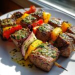 Close-up of grilled steak BBQ skewers topped with vibrant Cowboy Butter, featuring peppers and onions.