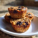 Three baked oatmeal cups with blueberries stacked on a white plate, perfect for Easy Fun Breakfast Ideas Mini.