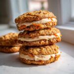 A stack of three Cozy Carrot Cake Cookies Cream sandwiches filled with thick cream cheese frosting.