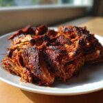 Close-up of shredded, richly seasoned, and crispy Slow Cooker Carnitas piled on a white plate.