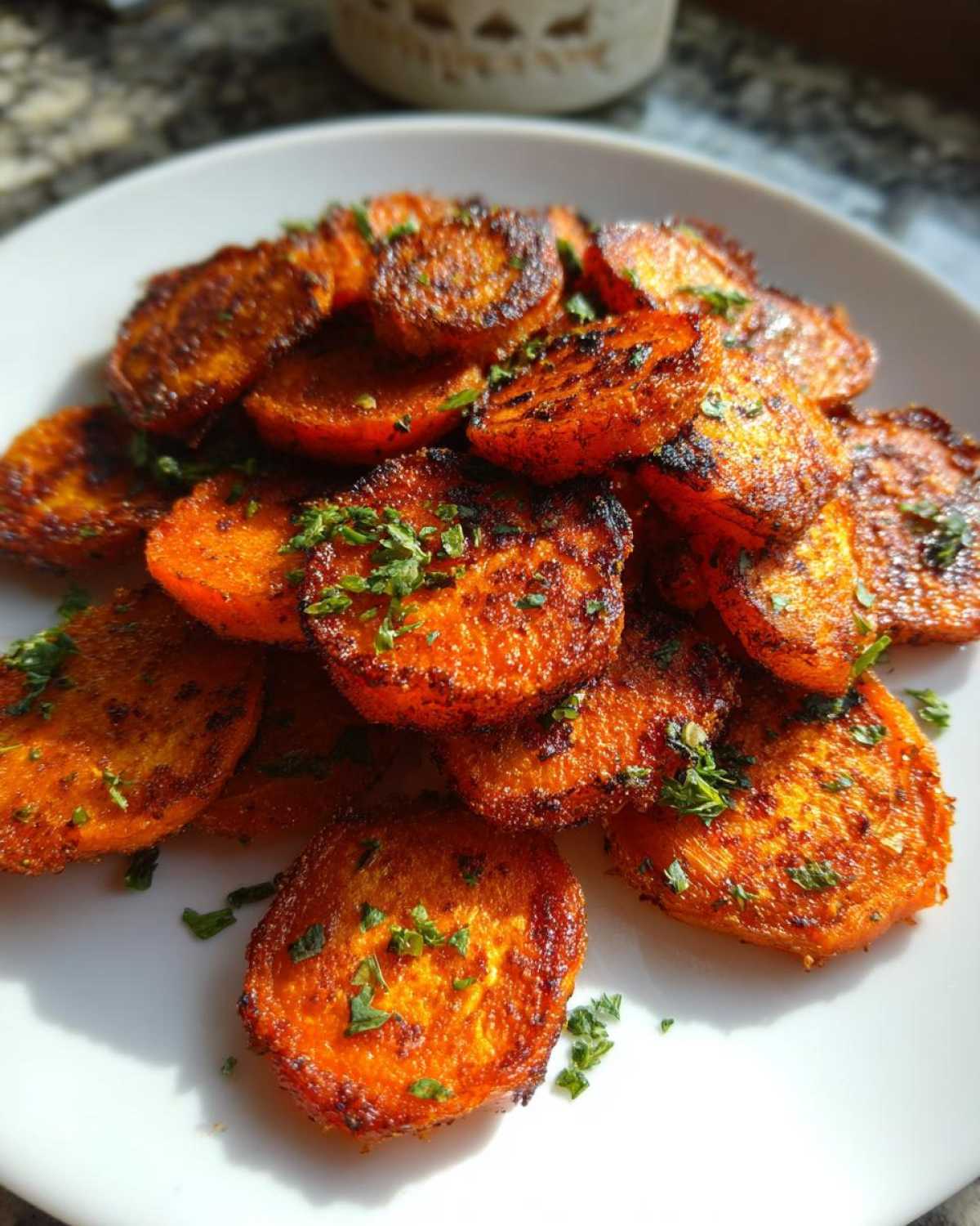 Close-up of oven roasted Crispy Smashed Carrot Bites, bright orange and seasoned, garnished with parsley.