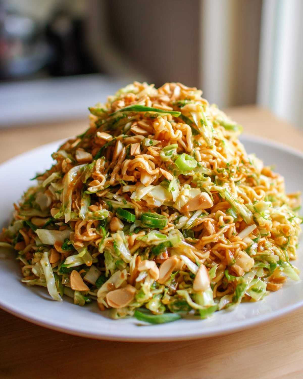 A mound of Crunchy Asian Ramen Noodle Salad featuring shredded cabbage, green onions, and toasted almonds tossed in dressing.