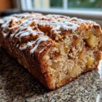 Close-up of a freshly baked Easy Amish Apple Fritter Bread loaf drizzled with white icing.