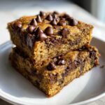 Two stacked squares of Easy Bakerystyle Chocolate Chip Banana bars, topped with melted chocolate chips.