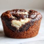 A single, rich chocolate muffin swirled with a creamy white center, representing Easy Chocolate Cream Cheese Muffins.