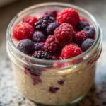 Close-up of overnight oats in a jar topped with frozen raspberries, blueberries, and blackberries for Easy Healthy Breakfast Inspiration Healthy.