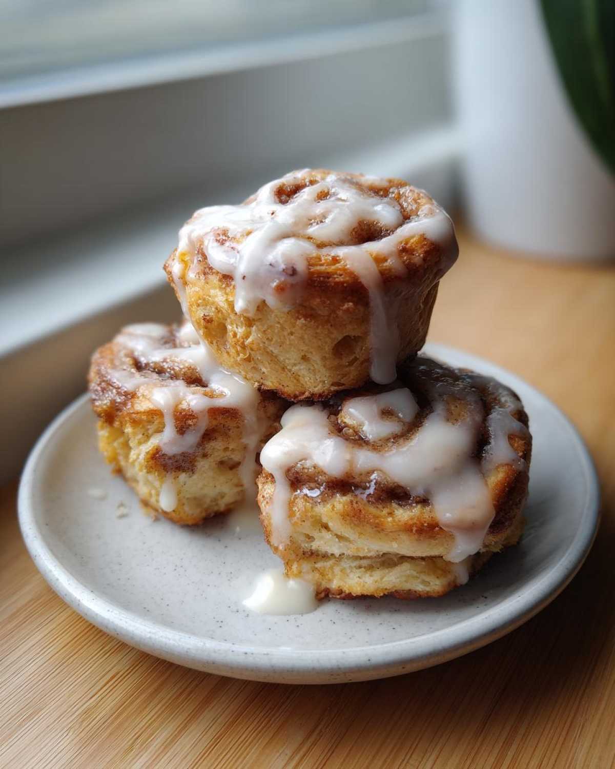 Three stacked Easy Heavenly Cinnamon Bun Scones drizzled generously with white icing.