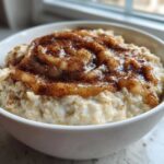 A close-up of Easy Low Sugar Applesauce Oatmeal topped with applesauce and cinnamon in a white bowl.