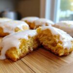 A soft, yellow citrus cookie, broken in half to show the texture, topped with thick white glaze, part of several Easy Spring Cookie Recipes Citrus.