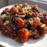 Plate of sticky, glazed Gochujang Mushrooms topped with sesame seeds and sliced green onions.