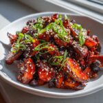 A close-up of glossy, red-glazed Gochujang Mushrooms That Taste Great, garnished with sesame seeds and sliced green onions.