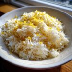 A bowl of fluffy white Greek Lemon Rice generously topped with bright yellow lemon zest.