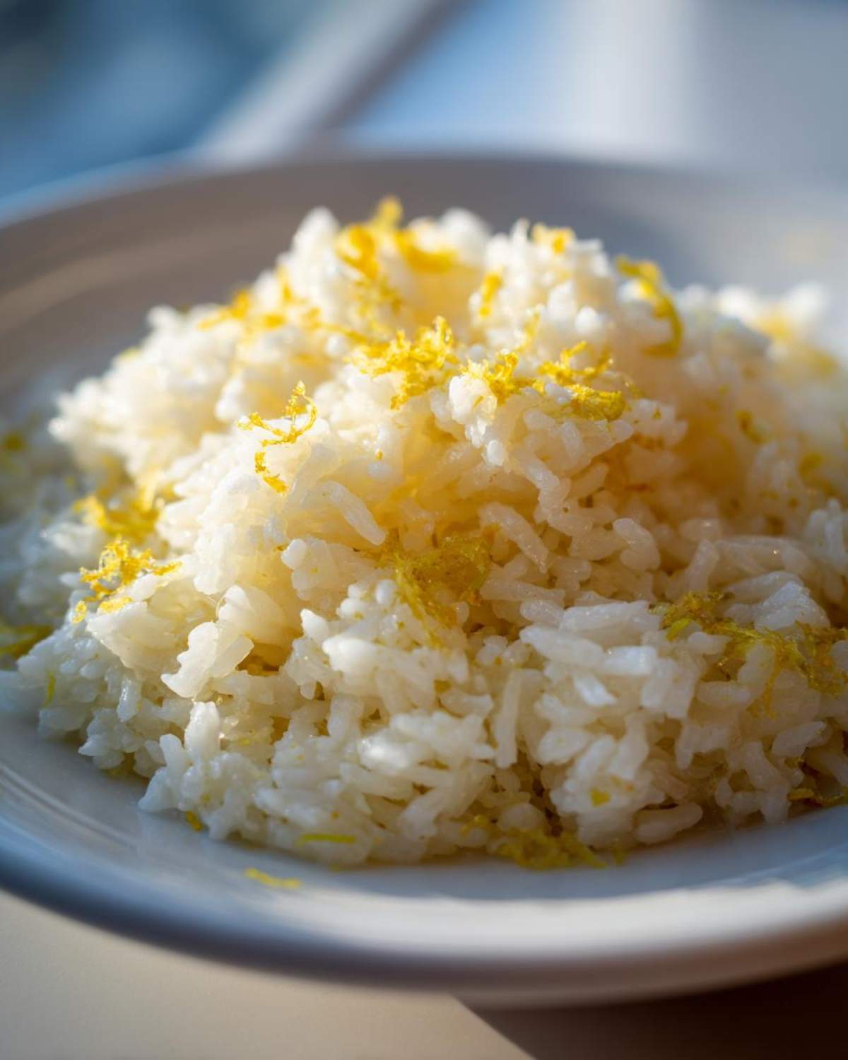 Close-up of fluffy white Greek Lemon Rice topped generously with bright yellow lemon zest.
