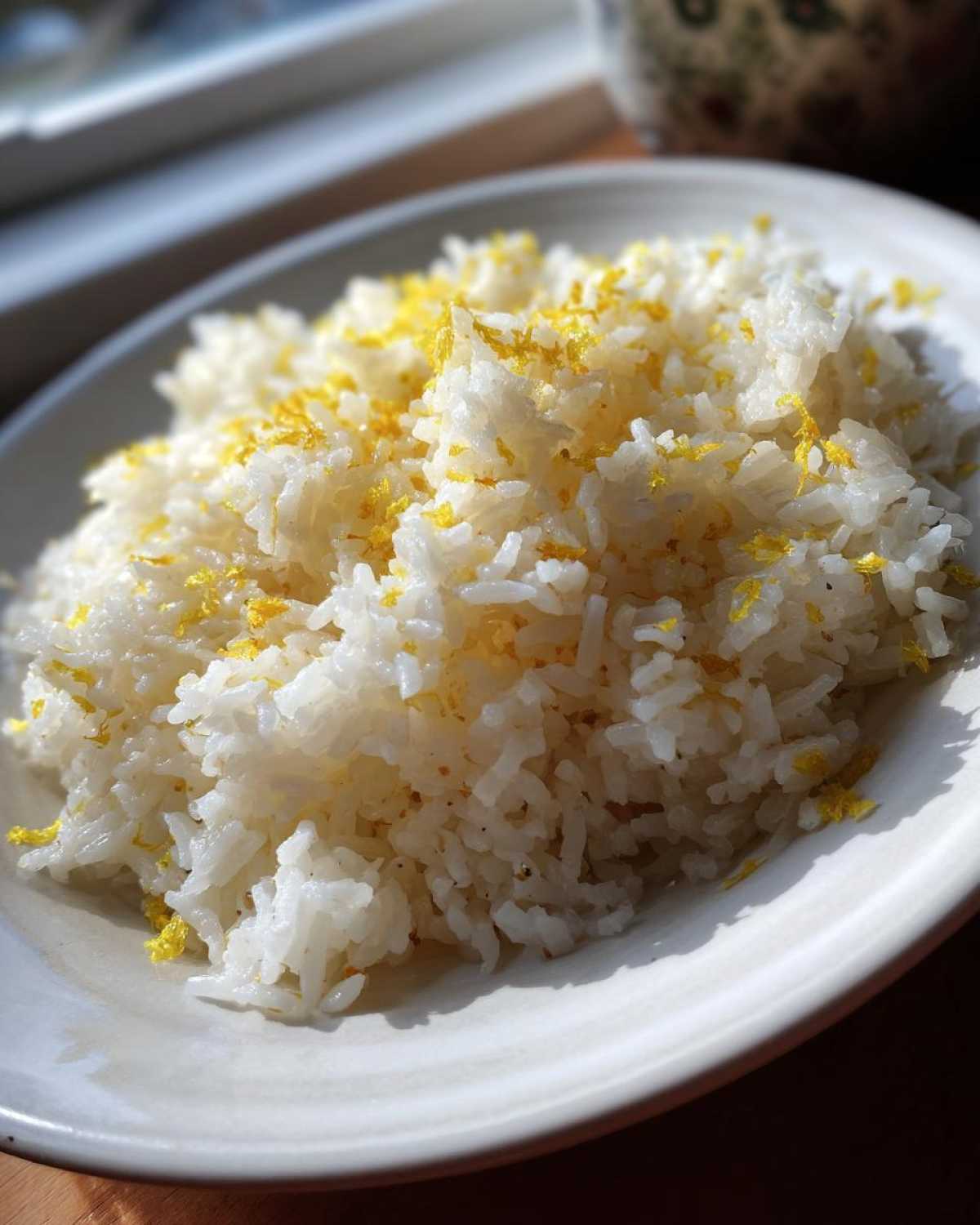 Close-up of fluffy white Greek Lemon Rice garnished generously with bright yellow lemon zest.