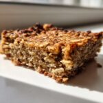 A close-up, sunlit shot of a single square of Healthy Banana Oatmeal Bars 5Ingredient showing texture.