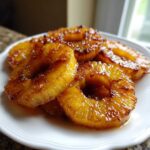 Close-up of glistening, caramelized Honey Lime Roasted Pineapple rings stacked on a white plate.