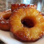 Close-up of three glistening, caramelized rings of Honey Lime Roasted Pineapple on a white plate.