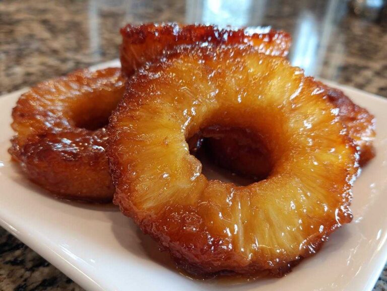 Close-up of three glistening, caramelized rings of Honey Lime Roasted Pineapple on a white plate.