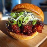 Close-up of a delicious Korean BBQ Chicken Sandwich with glossy sauce, slaw, and green onions.