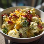 A close-up of a creamy Loaded Broccoli Cauliflower Salad Low Carb Incredible topped with shredded cheddar cheese and crispy bacon bits.