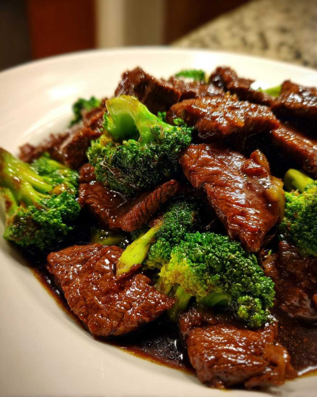 A close-up of glossy, saucy slices of beef mixed with vibrant green broccoli florets, part of the Low Carb Mongolian Beef Recipe.