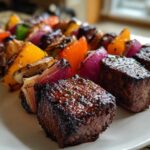 Close-up of glistening, perfectly grilled Steak Kabobs featuring seared beef cubes and colorful bell peppers and red onions.
