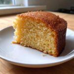 A close-up of a moist slice of Microwave Greek Yogurt Cake with a golden-brown top, served on a white plate.
