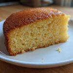 Close-up of a moist, golden slice of Microwave Greek Yogurt Cake on a white plate.