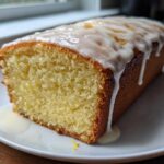 Close-up of a slice of Moist Lemony Lemon Bread Glazed, showing the crumb texture and thick white icing dripping down the side.