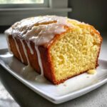A thick slice of Moist Lemony Lemon Bread Glazed showing its crumb texture on a white plate.