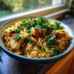 Close-up of a blue bowl filled with seasoned One Pot Chicken Shawarma Rice, topped generously with fresh chopped parsley.