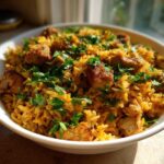 A close-up of a white bowl filled with flavorful One Pot Chicken Shawarma Rice, topped with fresh parsley.