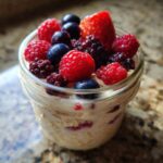 Overnight oats topped generously with fresh raspberries, blueberries, blackberries, and a strawberry slice—perfect Easy Healthy Breakfast Inspiration.