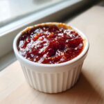 Close-up of thick, rich, dark red Pineapple Jalapeno Bourbon BBQ Sauce in a white ramekin.