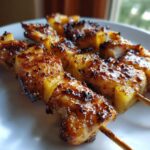 Close-up of beautifully caramelized Pineapple Teriyaki Chicken Skewers resting on a white plate.