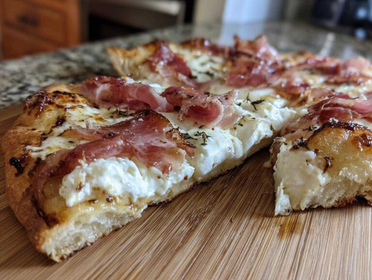 A close-up view of a slice of Prosciutto Honey Burrata Pizza showing creamy burrata, draped prosciutto, and a drizzle of honey on a wooden board.