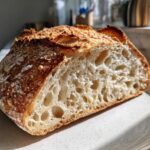 Cross-section of artisan sourdough bread showing an open, airy crumb structure and a dark, crackly crust.