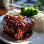 A close-up of a Teriyaki Pineapple Chicken Thighs piece covered in thick, glossy sauce, served with white rice and broccoli.